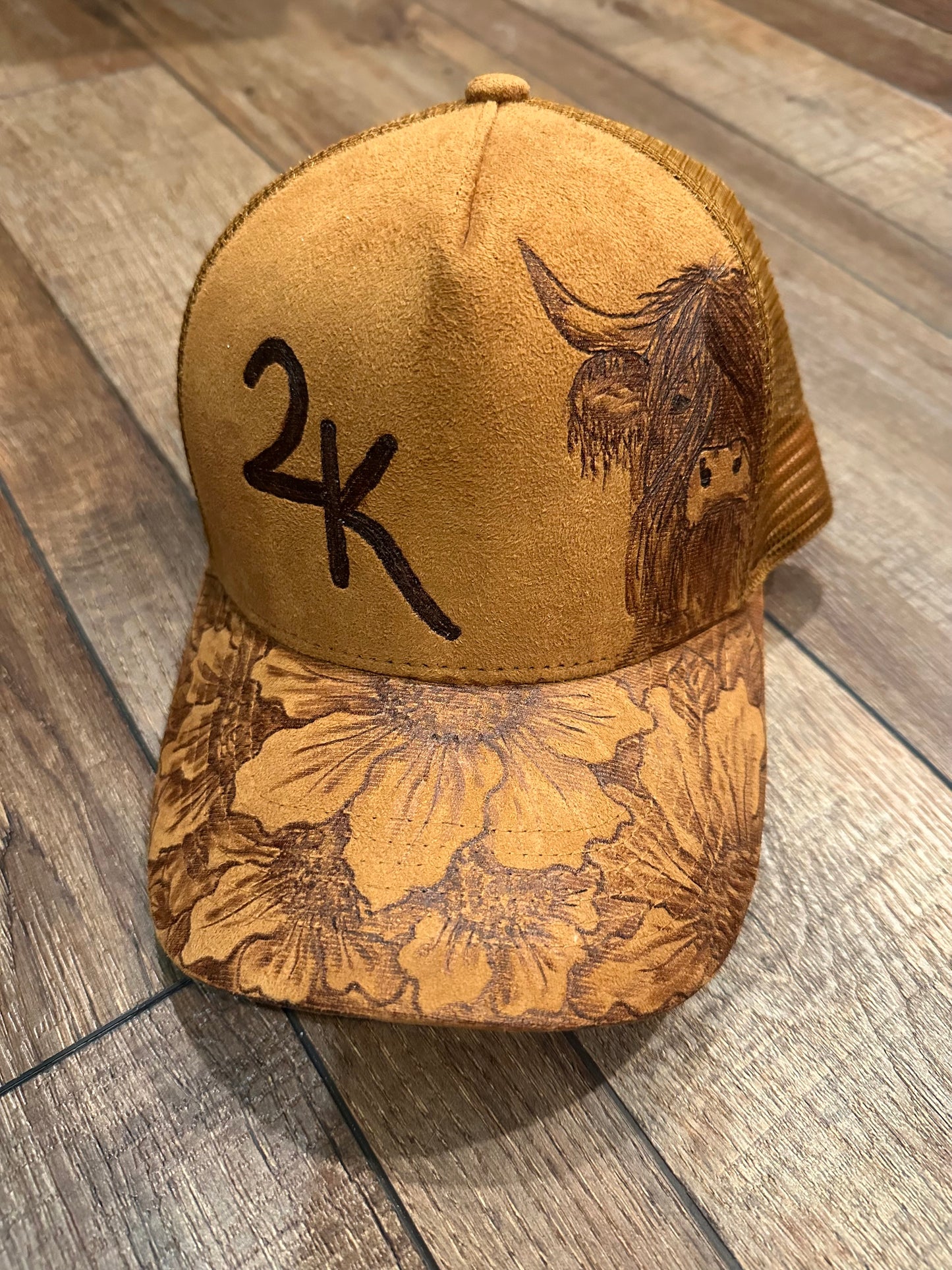 Brown cap with floral patterns and a bull design on a wooden floor