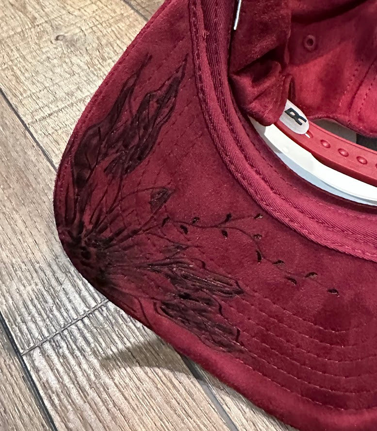 Maroon cap with floral embroidery on a wooden floor