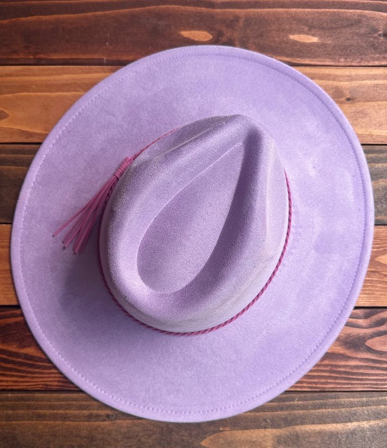 Purple cowboy hat with a feather on a wooden surface