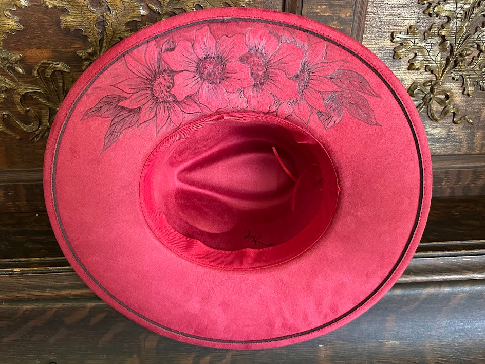 Red cowboy hat with floral patterns on a wooden surface