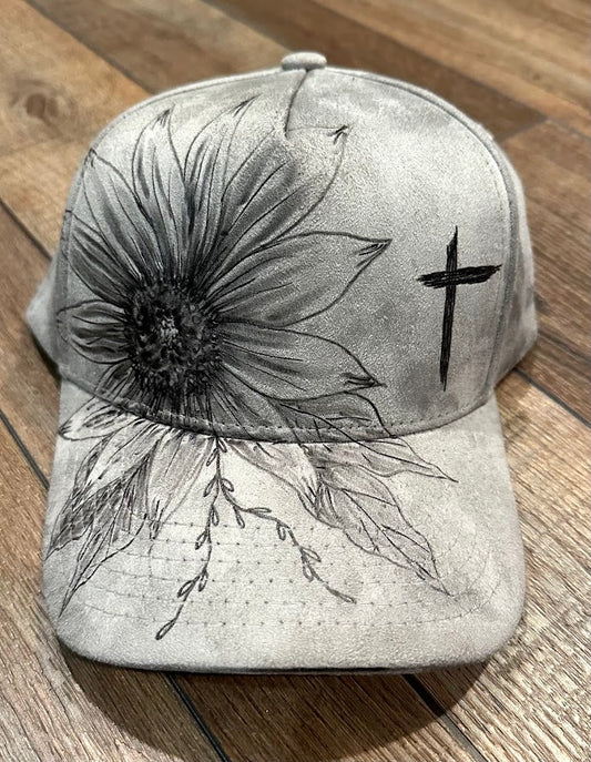 Cap with black floral design and cross on a wooden surface
