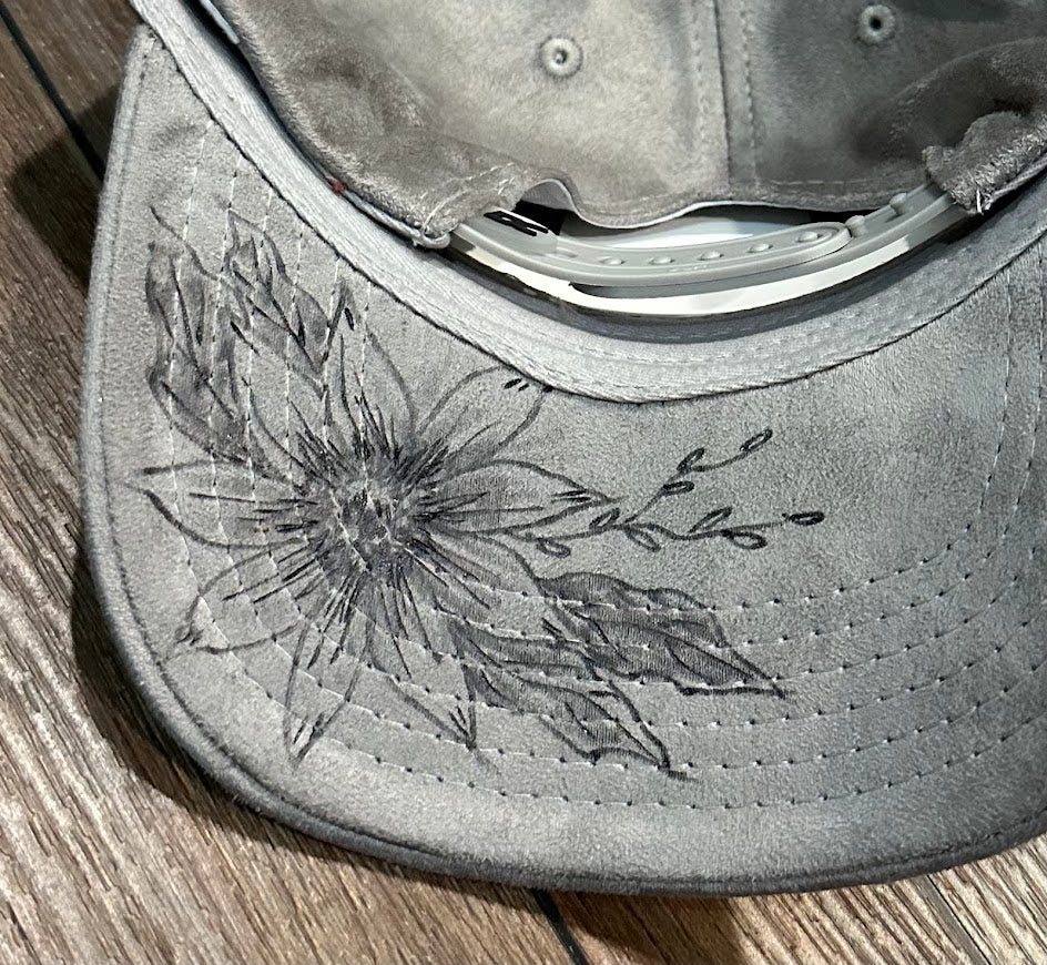 Gray cap with floral embroidery on a wooden surface