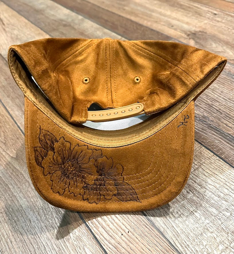 Brown leather bag with floral embroidery on a wooden surface