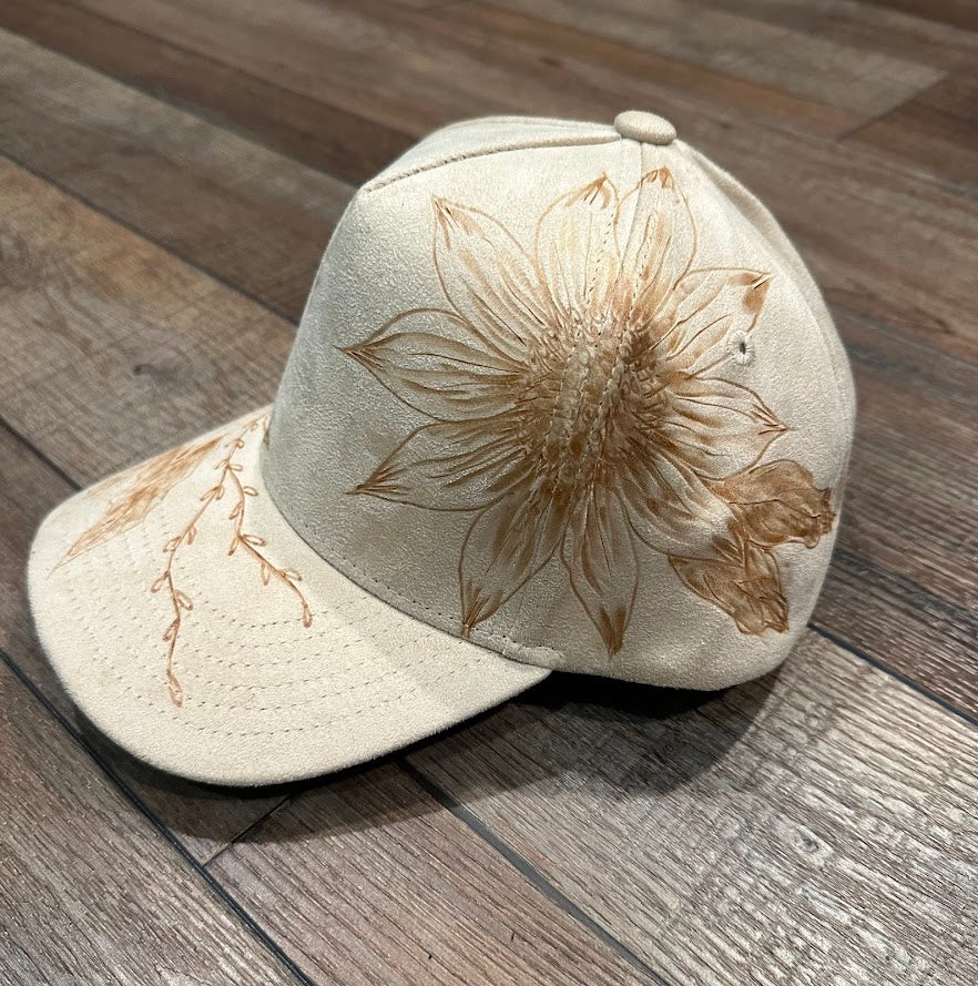 Beige cap with brown floral embroidery on a wooden surface