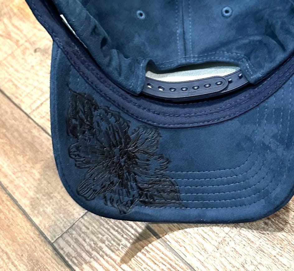 Blue cap with a black floral design on a wooden surface