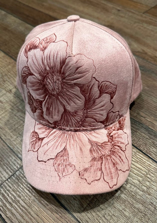Pink cap with floral designs on a wooden surface