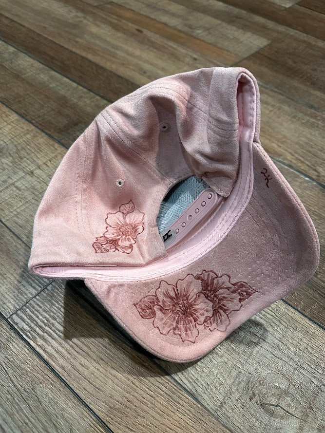 Pink cap with floral embroidery on a wooden floor