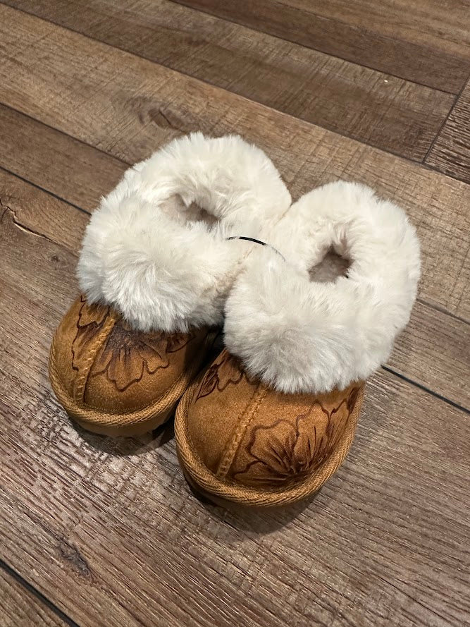 Pair of brown slippers with white fur on a wooden floor