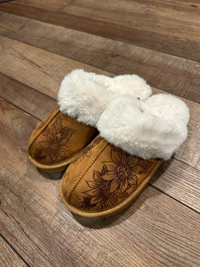 Pair of slippers with white fur lining on a wooden floor