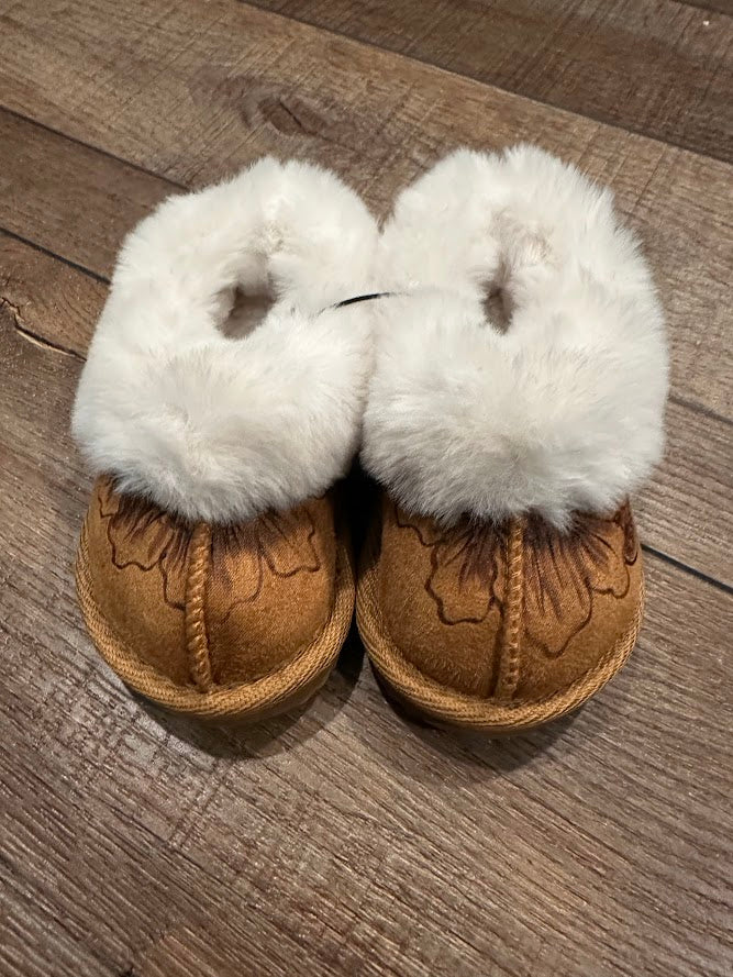 Pair of brown moccasin slippers with white fur on a wooden surface