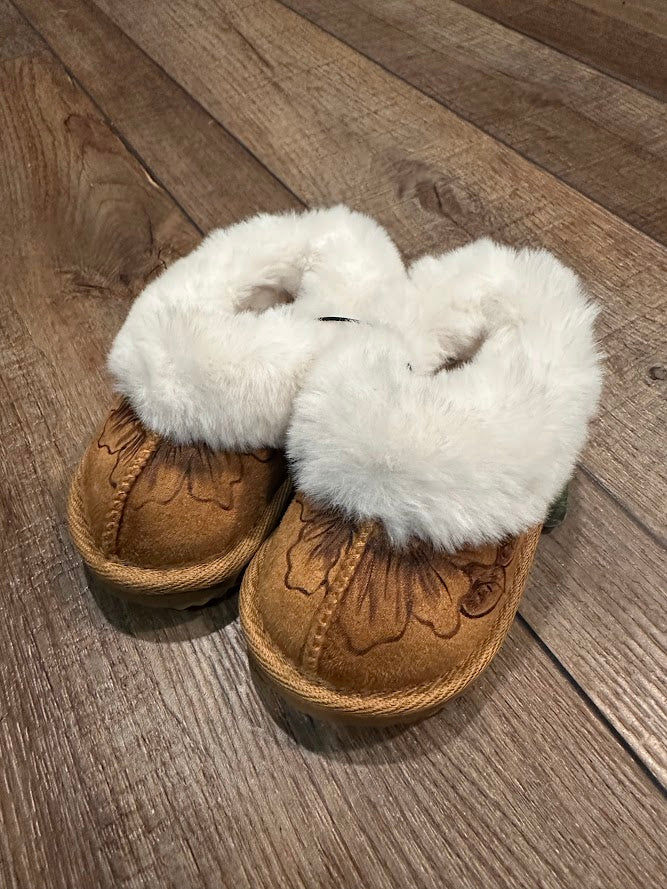 Pair of brown slippers with white fur on a wooden floor