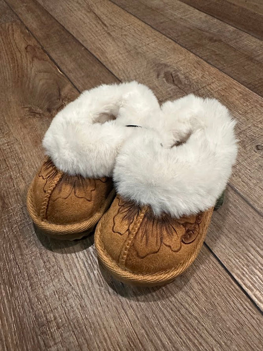 Pair of brown slippers with white fur on a wooden floor