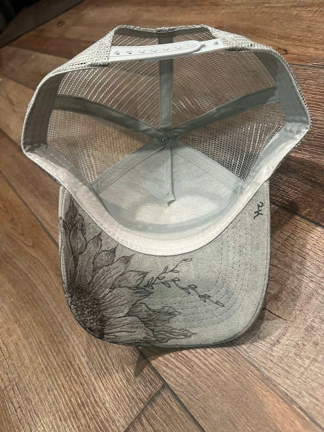 Gray mesh cap with floral design on a wooden surface