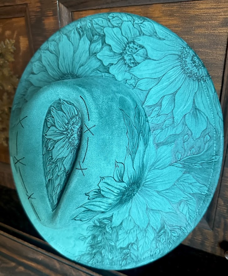 Turquoise hat with floral embossing on a wooden surface