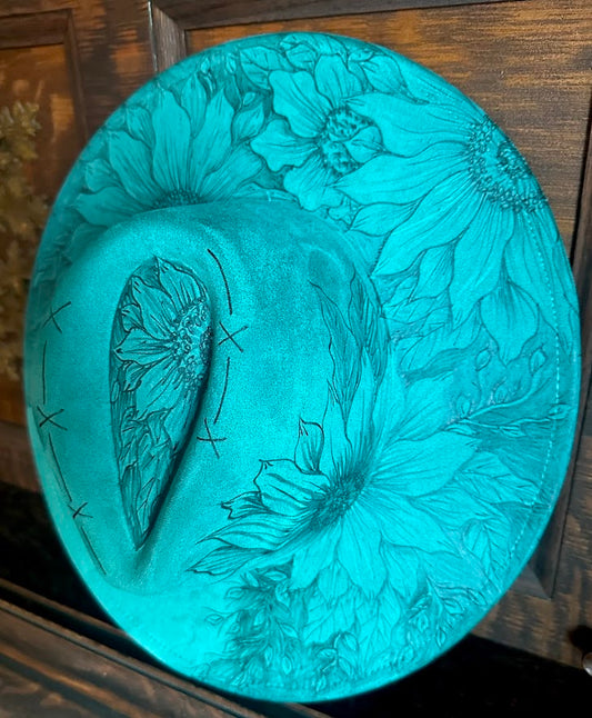 Turquoise hat with floral embossing on a wooden surface