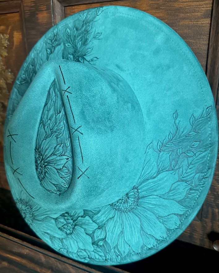 Turquoise decorative plate with floral and butterfly design on a wooden surface