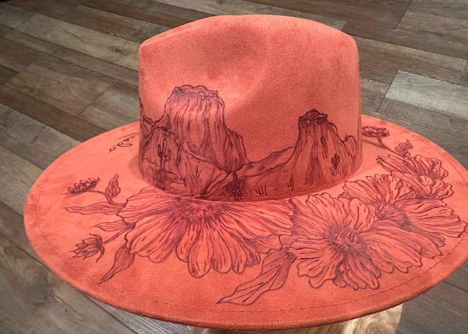 Red hat with mountain and floral design on a wooden floor