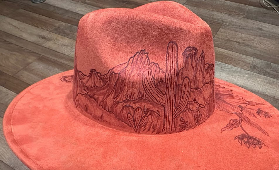 Red hat with desert landscape design on a wooden floor