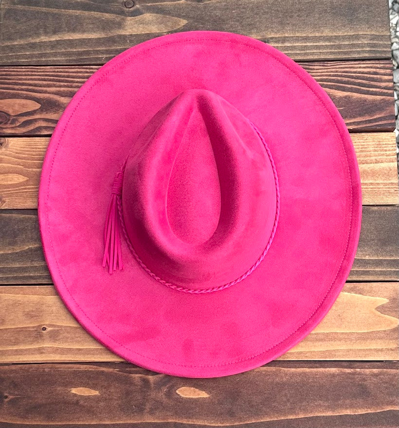 Pink cowboy hat with a feather on a wooden surface