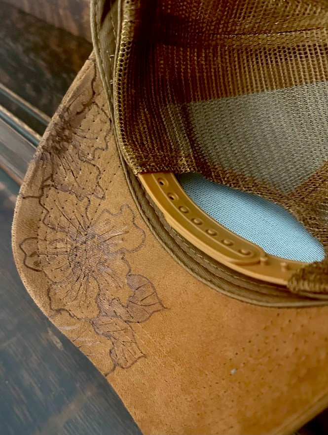 Close-up of a brown leather boot with floral embroidery on a reflective surface