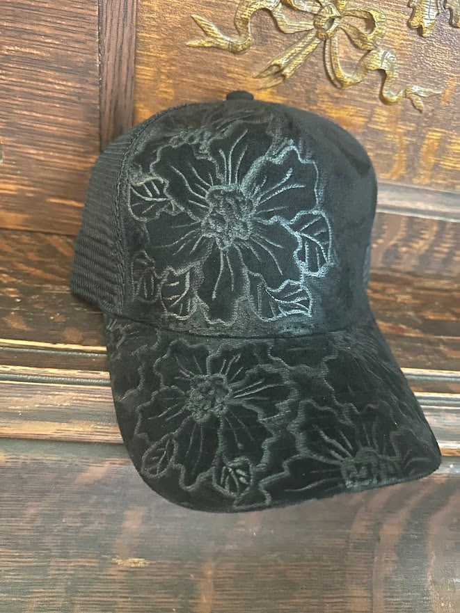 Black floral embroidered cap on a wooden surface