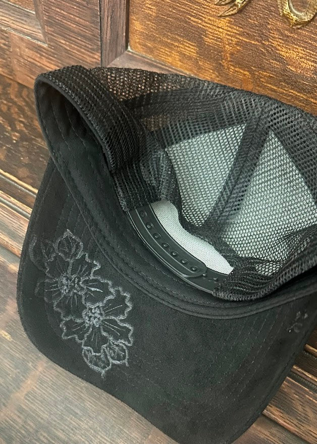 Black mesh cap with floral embroidery on a wooden surface