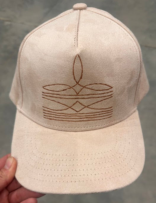Beige cap with a geometric design held by a hand against a gray background