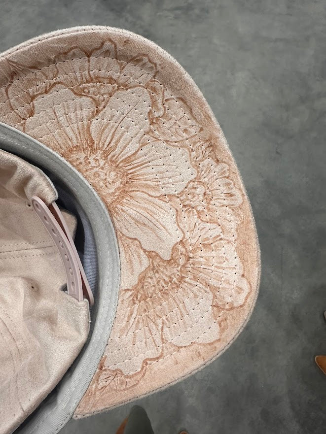 Close-up of a textured beige hat with floral patterns on a gray surface