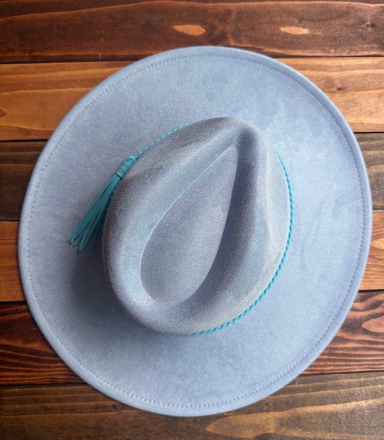 Light blue cowboy hat with a feather on a wooden surface