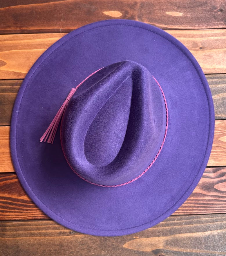 Purple cowboy hat with a pink band on a wooden surface