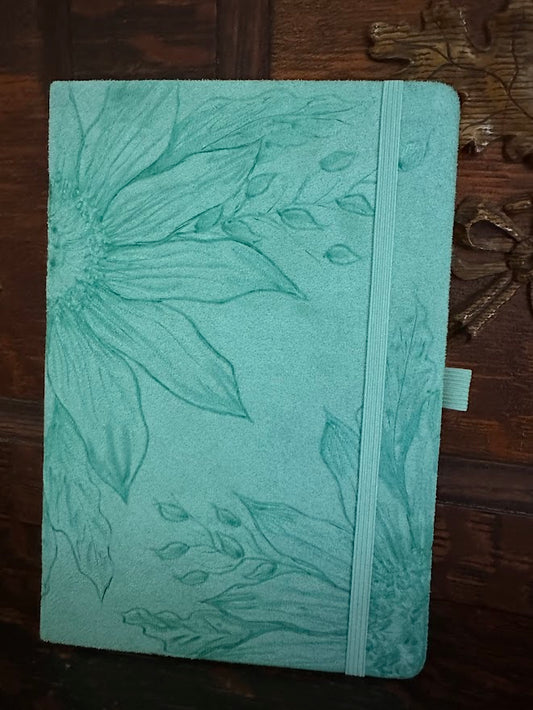 Green notebook with floral embossing on a wooden surface