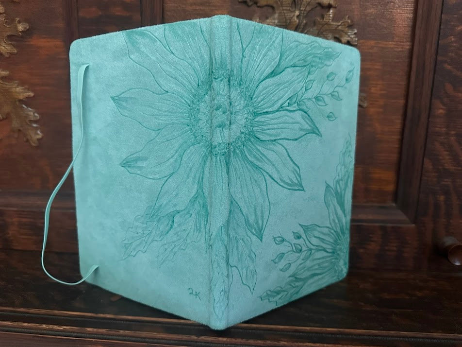 Teal notebook with floral design on a wooden surface