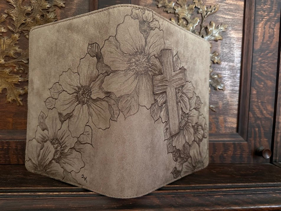 Decorative cushion with floral and cross design on a wooden surface