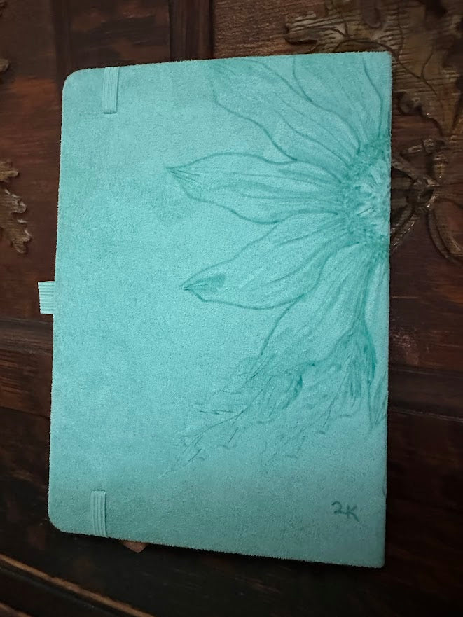 Light blue notebook with floral design on a wooden surface